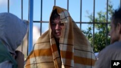 Raia wa Afghanistan aliyefunikwa na blanketi, anazungumza na wahamiaji wengine katika shule ya zamani inayotumiwa kama makazi ya muda kwenye kisiwa cha Kythira, kusini mwa Ugiriki, Ijumaa, Oktoba 7, 2022.
