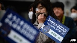 People queue to see the Tokyo 2020 Olympic flame on display outside the railway station in Tono, Iwate prefecture on March 22, 2020. - The flame arrived in Japan to a scaled-down welcoming ceremony on March 20 as doubts grew over whether the 2020…