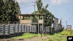 FILE - Rwandan security forces look out from their sentry box as Congolese soldiers patrol on foot on their side of the border crossing with Rwanda in Goma, Congo, on June 17, 2022.
