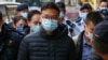 Stand News chief editor Patrick Lam is brought to the news outlet's office building in handcuffs after police were deployed to search the premises in Hong Kong's Kwun Tong district on Dec. 29, 2021. 