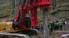 India's Minister of State of Road Transport and Highways VK Singh, right, inspects earth boring machine deployed to drill a vertical hole into the collapsed tunnel to rescue the 41 men in India's Uttarakhand state on Nov. 26, 2023. 