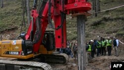 India's Minister of State of Road Transport and Highways VK Singh, right, inspects earth boring machine deployed to drill a vertical hole into the collapsed tunnel to rescue the 41 men in India's Uttarakhand state on Nov. 26, 2023. 