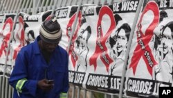A man makes a call on a mobile phone as he passes past a World AIDS Day banners on the perimeter of an office building in Sandton, Johannesburg, South Africa, Dec. 1, 2014. 