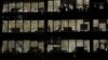 FILE - Workers are seen in office windows in the financial district of Canary Wharf in London, Nov. 3, 2015. 