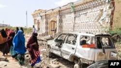 FILE - Wanawake wakipita katika nyumba na gari yaliyoharibiwa kabisa na mlipuko uliofanywa na wapiganaji wa al-Shabab mjini Mogadishu, Somalia, Feb. 16, 2022. 