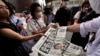An employee distributes extra editions of the Yomiuri Shimbun newspaper reporting on Japan's former Prime Minister Shinzo Abe was shot, July 8, 2022, in Tokyo.