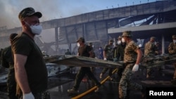 Рятувальники та військовослужбовці працюють на місці торгового центру, в який влучив у російський ракетний удар, у Кременчуці на Полтавщині, Україна 27 червня 2022 року. Знімок зроблений 27 червня 2022 року. REUTERS/Анна Войтенко