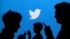 ARCHIVO - Las siluetas de las personas que sostienen teléfonos móviles contra un fondo proyectado con el logotipo de Twitter en esta fotografía ilustrativa tomada el 27 de septiembre de 2013.