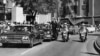 FILE - Seen through the foreground convertible's windshield, President John F. Kennedy's hand reaches toward his head within seconds of being fatally shot as first lady Jacqueline Kennedy holds his forearm in Dallas, on Nov. 22, 1963.