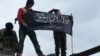 FILE - Rebels from al-Qaida-affiliated Jabhat al-Nusra wave their brigade flag as they stand atop a Syrian air force helicopter at Taftanaz air base, Jan. 11, 2013.