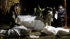 FILE - Ukrainian policemen inspect the bodies of persons that were killed by a Russian rocket attack that killed 51 people in the village of Hroza near Kharkiv, Ukraine, Oct. 5, 2023.