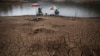 FILE - Men fish next to cracked ground as the Atibainha dam lake dries up due to a prolonged drought in Nazare Paulista, Sao Paulo state, Brazil, Oct. 17, 2014. 
