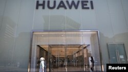 人们走过北京街头的华为专卖店。 （2021年6月3日）