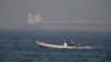 A fishing boat speeds past an oil tanker in the distance in Fujaira, United Arab Emirates, June 15, 2019. The Kokuka Courageous, one of two oil tankers targeted in apparent attacks in the Gulf of Oman, was brought to the United Arab Emirates' eastern coa