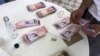 Una mesera cuenta bolívares con los que se pagaron un almuerzo para cuatro personas en un restaurante de Caracas.