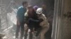 Civil defense members evacuate a woman from a damaged building after airstrikes in the rebel held area of old Aleppo, Syria, April 22, 2016.