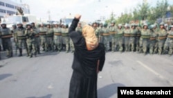資料照：一名新疆維吾爾婦女舉拳向一隊中國武警士兵表示抗議。 (照片來自世界維吾爾代表大會網站)