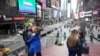 A couple kisses as they pose for a photo at the top of the TKTS stairs, March 10, 2020, in New York's Times Square.