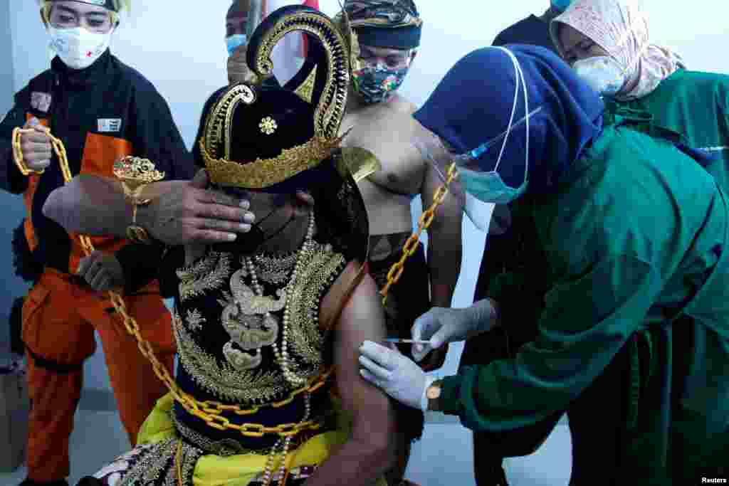 Seorang petugas medis menyuntikkan vaksin Sinovac kepada seorang pria yang mengenakan kostum &#39;Wayang&#39;, saat Indonesia melakukan vaksinasi massal Covid-19 di sebuah rumah sakit di Solo, Jawa Tengah, 22 Januari 2021. (Foto: Maulana Surya /&nbsp;Antara via Reuters)