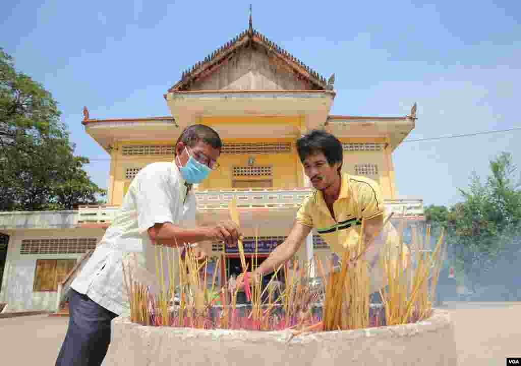 បុរសពីរនាក់កំពុងអុជធូបនៅវត្តនិរោធរង្សី រាជធានីភ្នំពេញ ក្នុងអំឡុងពេលប្រារព្ធពិធីបុណ្យចូលឆ្នាំខ្មែរថ្ងៃទី២ នៅថ្ងៃទី១៤ ខែមេសា ឆ្នាំ២០២០។ (កាន់ វិច្ឆិកា/VOA)