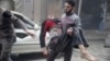 A resident carries an injured man through a site damaged from what activists said was an airstrike by forces loyal to Syria's President Bashar al-Assad on the main field hospital in the town of Douma, Syria, Oct. 29, 2015.