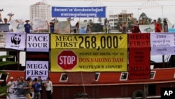 Cambodian non-governmental organization (NGOs) activists shout slogans during a protest against a proposed Don Sahong dam, in a tourist boat along the Tonle Sap river, in Phnom Penh, Cambodia, Thursday, Sept. 11, 2014. The activists use a tour boat to campaign their opposition against the building of the mega dam. Authority on Thursday banned more than a hundred NGOs activists included Buddhist monks for protests on the tourist boats, saying activists, for their event to share the concerns of more than a quarter of million people calling on Mega First Corporation to suspend construction of the controversial Don Sahong hydropower project on the Mekong River in Laos. (AP Photo/Heng Sinith) 