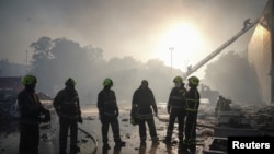 Los equipo de rescate se toman un respiro tras apagar el fuego en un centro comercial de la ciudad de Kremenchuk, en Ucrania, tras recibir el impacto de misiles rusos, el 27 de junio de 2022.