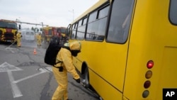 Український працівник у протирадіаційному костюмі перевіряє рівень радіації в автобусі під час тренувань у Запоріжжі, 29 червня 2023 р. AP Photo/Evgeniy Maloletka
