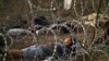 FILE - Afghan refugees sleep next to razor-wire barrier at the Serbian side of Hungary's border fence with Serbia, Sept. 17, 2015.