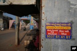 An advertising poster pasted on a shop at Dingucha village in Gandhinagar, India, Nov. 12, 2024. The poster reads in Gujarati "Make your dream of going abroad come true," on top and "Payment after visa."