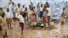 FILE - Burundian refugee children stand in the mud near to tents holding hundreds of other refugees who have fled from Burundi, at the Gashora refugee camp, in the Bugesera district of Rwanda, April 21, 2015.