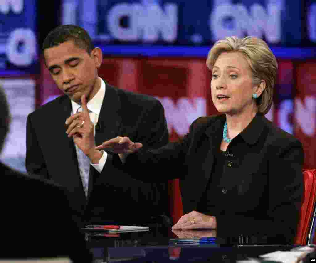 សមាជិក​ព្រឹទ្ធសភា​លោក Barack Obama ចង្អុល​បង្ហាញ​ពី​ពេលវេលា ស្រប​ពេល​សមាជិក​ព្រឹទ្ធសភា​លោកស្រី Hillary Rodham Clinton ធ្វើ​ការ​ឆ្លើយតប​នឹង​សំណួរ​មួយ​អំឡុងពេល​ការ​ជជែក​ដេញដោល​ដណ្តើម​តំណែង​ប្រធានាធិបតី​ក្នុង​ក្រុង Los Angeles កាល​ពី​ថ្ងៃ​ព្រហស្បតិ៍ ទី​៣១ ខែ​មករា ឆ្នាំ​២០០៨។