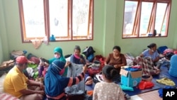 People who are displaced by floods sift through donated clothings at a temporary shelter in East Lewoleba, on Lembata Island, East Nusa Tenggara province, Indonesia, Tuesday, April 6, 2021. Multiple disasters caused by torrential rains in eastern…