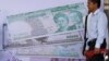 Cambodian men stand near local and international currencies poster during an inauguration ceremony of the Cambodia Securities Exchange in Phnom Penh, file photo. 