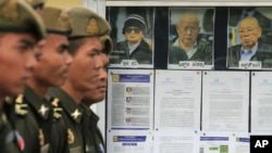 Cambodian military officials line up in front the top leaders of Khmer Rouge portraits, from right, former Khmer Rouge Foreign Minister Ieng Sary, former Khmer Rouge head of state Khieu Samphan, and former Deputy Secretary Nuon Chea, during the second d