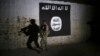 FILE - An Iraqi soldier inspects a recently-discovered train tunnel, adorned with an Islamic State group flag, that belonged to the former Baghdad to Mosul line, that was turned into a training camp for IS fighters, in western Mosul, Iraq, March 1, 2017.