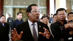 Cambodian Prime Minister Hun Sen, foreground, gestures as his answers the journalists question at National Assembly, in Phnom Penh, Cambodia, Monday, July 28, 2014.