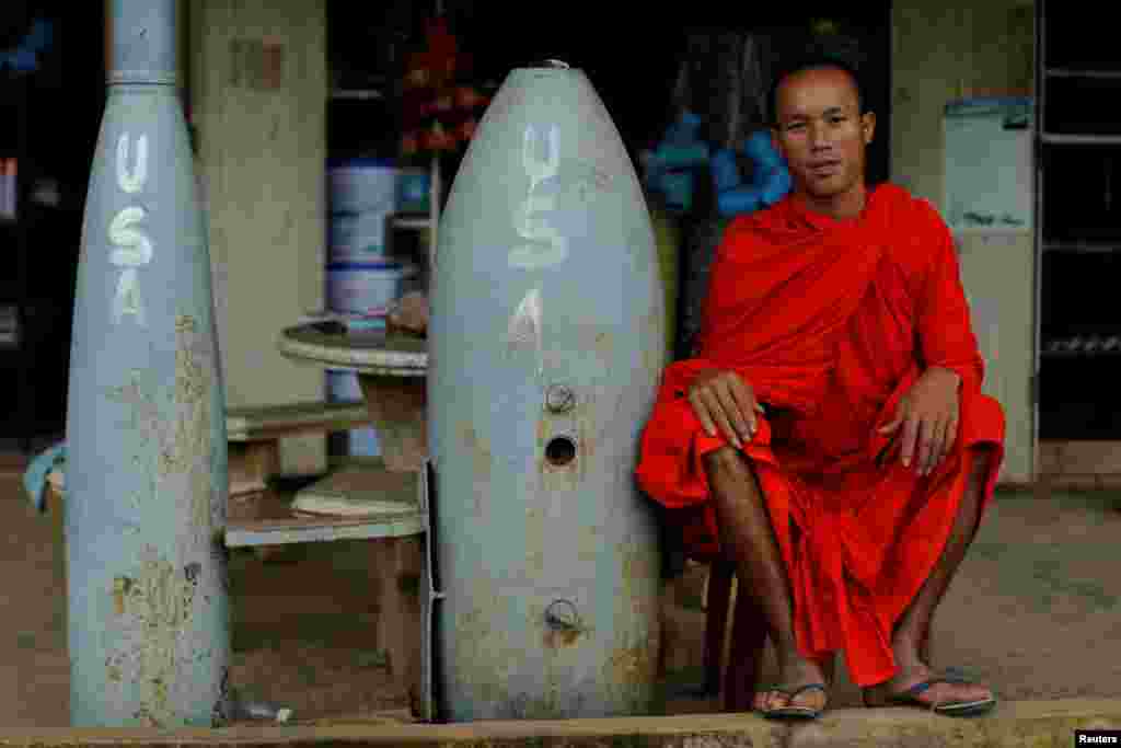 ព្រះសង្ឃ​ពុទ្ធសាសនា​មួយ​អង្គ​ឈរ​ជិត​គ្រាប់បែក​មិន​ទាន់​ផ្ទុះ ដែល​ត្រូវ​បាន​ទម្លាក់​ដោយ​កងកម្លាំង​ដែន​អាកាស​អាមេរិក​នៅ​អំឡុងពេល​សង្រ្គាម​វៀតណម ក្នុង​ក្រុង Xieng Khouang ប្រទេស​ឡាវ។