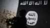 FILE - A member of the Iraqi forces walks past a mural bearing the logo of the Islamic State group in a tunnel that was reportedly used as a training center by the jihadists on the southern outskirts of Mosul, March 1, 2017.