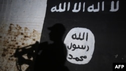 FILE - A member of the Iraqi forces walks past a mural bearing the logo of the Islamic State group in a tunnel that was reportedly used as a training center by the jihadists on the southern outskirts of Mosul, March 1, 2017.