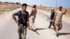 FILE - Libya Dawn fighters search for Islamic State militant positions during a patrol near Sirte.