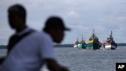 FILE - Fishing boats carrying recently rescued fishermen sail toward the town of Tual, Indonesia, Saturday, April 4, 2015. 