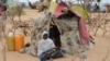 FILE - A woman is seen sitting in front of a tent in the Assaga refugee camp, set up by the U.N. for Nigerian refugees who fled to southeast Niger to escape Boko Haram militants, Sept. 16, 2015.