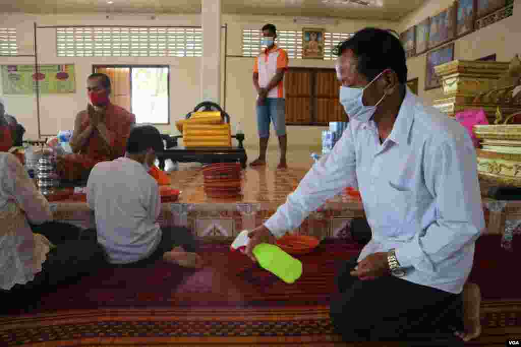 អាចារ្យវត្តកំពុងបាញ់អាល់កុលសម្លាប់មេរោគ នៅវត្តនិរោធរង្សី រាជធានីភ្នំពេញ ក្នុងអំឡុងពេលប្រារព្ធពិធីបុណ្យចូលឆ្នាំខ្មែរថ្ងៃទី២ នៅថ្ងៃទី១៤ ខែមេសា ឆ្នាំ២០២០។ (កាន់ វិច្ឆិកា/VOA)