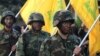 FILE - Hezbollah fighters hold their group's flags at a rally in Nabatiyeh, southern Lebanon, Nov. 7, 2014.