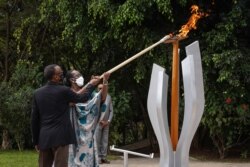 Rais wa Rwanda Paul Kagame (L) na mkewe Jeannette Kagame (R) wanawasha moto wa kumbukumbu ya miaka 27 ya Mauaji wa Kimbari yaliyotokea mwaka 1994 dhidi ya Kabila la Watutsi katika kituo cha kumbukumbu cha Kigali Genocide Memorial, Kigali, Rwanda, Aprili 7, 2021. (Photo by Simon Wohlfahrt / AFP)