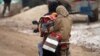 FILE - Internally displaced refugees carry a baby on a motorcycle during a snow storm inside Salkeen refugee camp, Northern Idlib countryside, Jan. 10, 2015. 