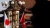 A Chinese paramilitary policeman is silhouetted as he stands guard near Japanese and Chinese national flags decorated near the Tiananmen Gate in Beijing, Friday, Oct. 26, 2018. 