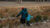 Un migrante guatemalteco y su hijo cruzan la frontera natural de Río Grande entre El Paso, estado de Texas, Estados Unidos, y Ciudad Juárez, estado de Chihuahua, México, en busca de asilo político el 26 de enero de 2021.