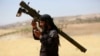 FILE - An Islamist Syrian rebel group Jabhat al-Nusra fighter talks on a walkie-talkie while carrying his weapon on Al-Khazan frontline of Khan Sheikhoun, northern Idlib province, Syria, May 17, 2014. 